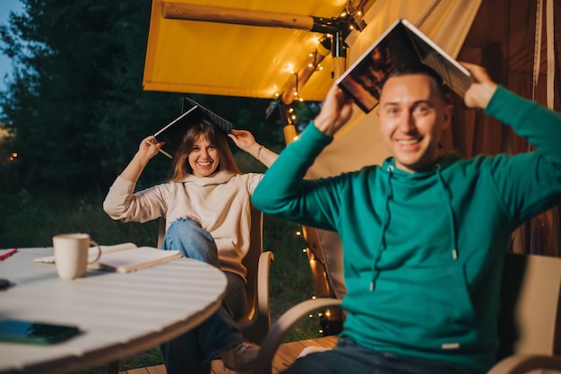 I liberi professionisti della coppia felice della famiglia si riposano dopo aver lavorato al laptop su un'accogliente tenda glamping in serata estiva Tenda da campeggio di lusso per vacanze all'aperto e vacanze Concetto di stile di vita