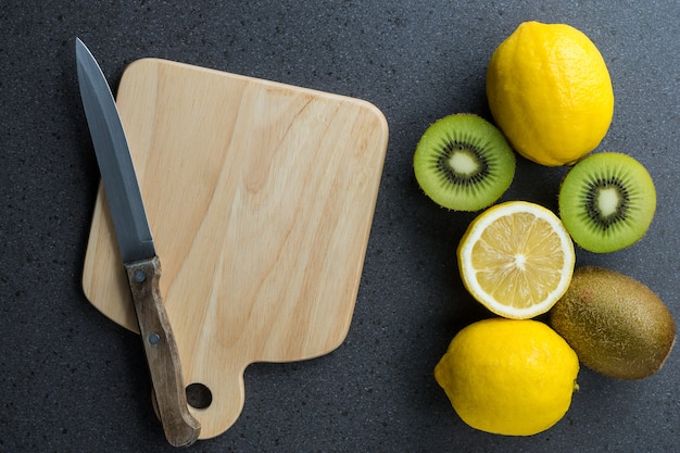 I limoni sono sopra il tagliere di legno con il coltello