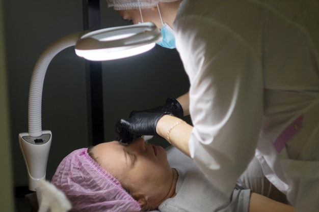 I maestri di bellezza realizzano il trucco permanente degli occhi con le loro mani Il microblading viene eseguito utilizzando un manip