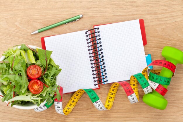 I manubri misurano il cibo sano e il blocco note per lo spazio di copia Fitness e salute
