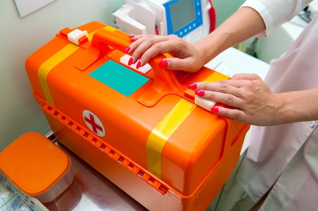 I medici mani sulla valigia arancione della prima emergenza medica