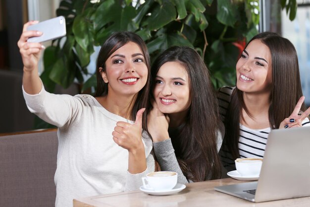 I migliori amici con il laptop insieme prendono selfie seduti al caffè
