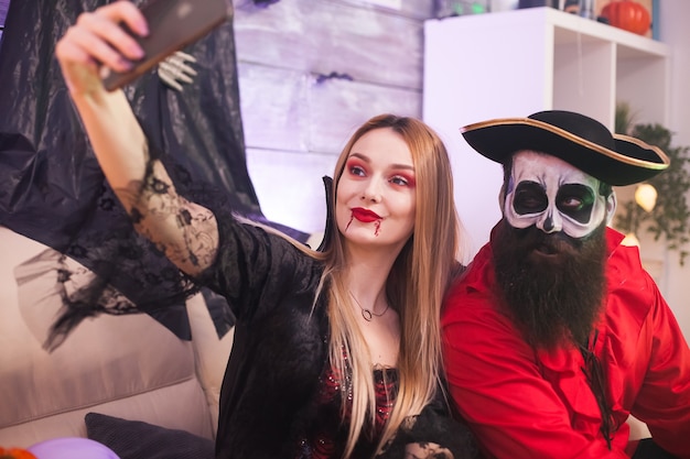 I migliori amici vestiti come pirati medievali e vampiri che si fanno selfie alla festa di halloween.