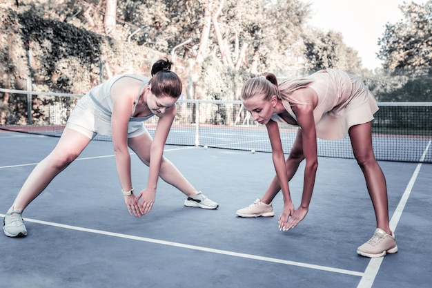 I migliori esercizi di stretching. Determinate due donne che si allungano in campo e si scaldano