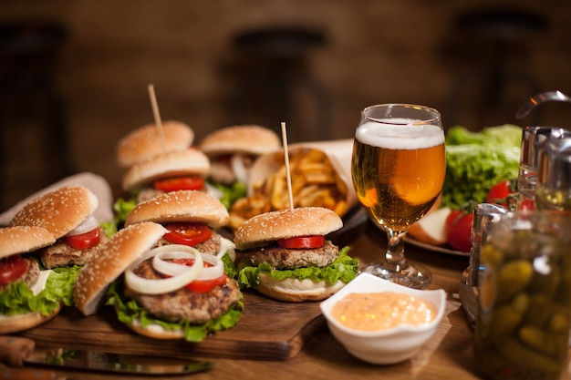 I migliori hamburger dell'happy hour con birra fredda su un tavolo di legno del ristorante. Patatine fritte. lattuga verde.