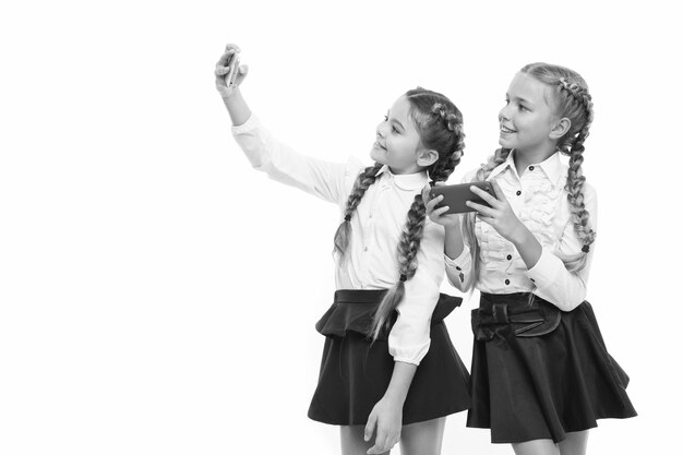 I migliori telefoni per scattare selfie Bambini piccoli che usano le fotocamere del telefono per scattare isolate su bianco Bambine che hanno lezioni sui telefoni cellulari I telefoni cellulari come strumenti educativi copiano lo spazio