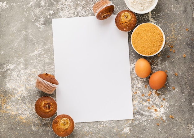 I muffin alla banana fatti in casa e gli ingredienti per cucinare sono disposti su un foglio bianco bianco Dessert vegano sano