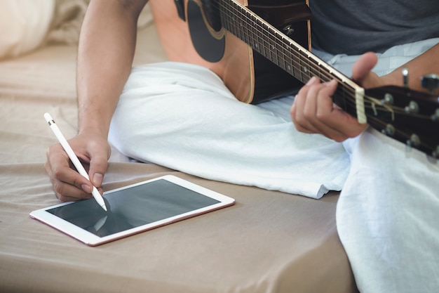 I musicisti suonano la chitarra e compongono canzoni usando il tablet.