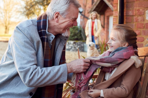 I nonni con la nipote fuori casa si preparano per andare a fare una passeggiata invernale