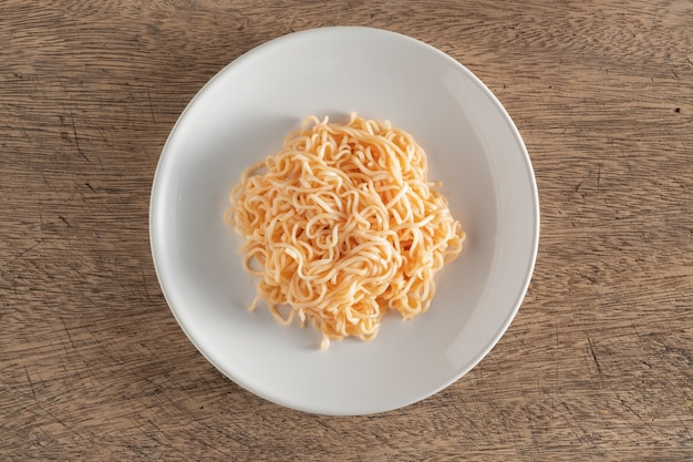 I noodles sono in un piatto bianco rotondo posizionato su un tavolo di legno.
