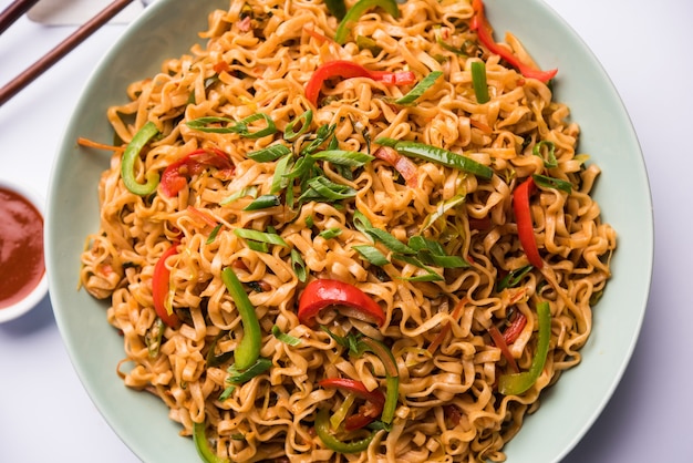 I noodles vegetariani di Schezwan sono noodles Hakka piccanti e gustosi saltati in padella con salsa e verdure. servito con le bacchette. messa a fuoco selettiva