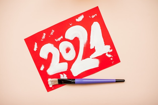 I numeri 2021 sono scritti in vernice bianca su un foglio di carta rosso. Nuovo anno