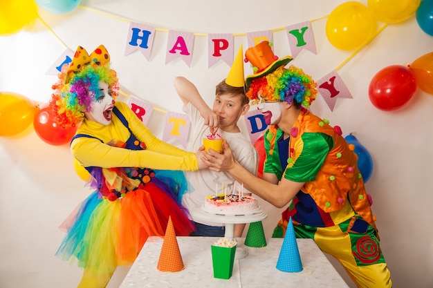 I pagliacci felici alla festa spengono le candeline sulla torta di compleanno