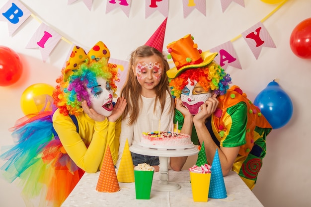 I pagliacci felici spengono le candeline sulla torta di compleanno durante le vacanze