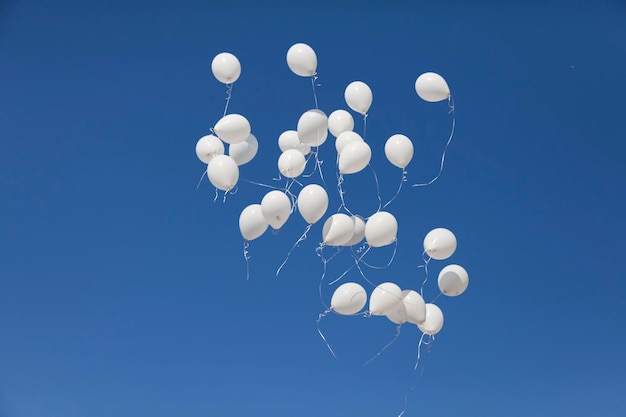 I palloncini bianchi si lanciano in un cielo blu più chiaro