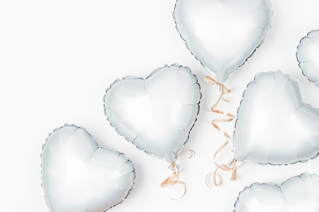 I palloni ad aria di lamina a forma di cuore su sfondo bianco. Concetto di amore. Celebrazione delle vacanze. Decorazione di San Valentino o matrimonio/addio al nubilato. Palloncino metallico