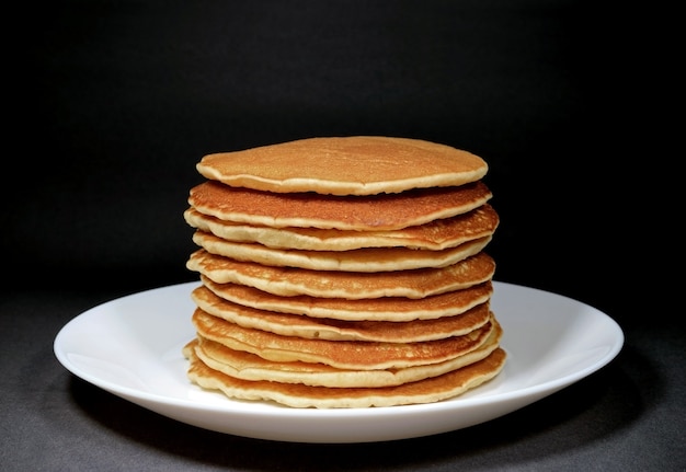 I pancake puri in su accatastati sono servito sul piatto bianco, isolato su fondo nero