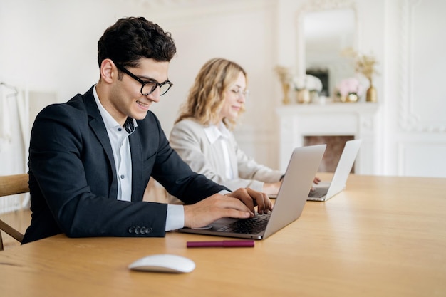 I partner un uomo e una donna che lavorano in ufficio usano i laptop sul posto di lavoro