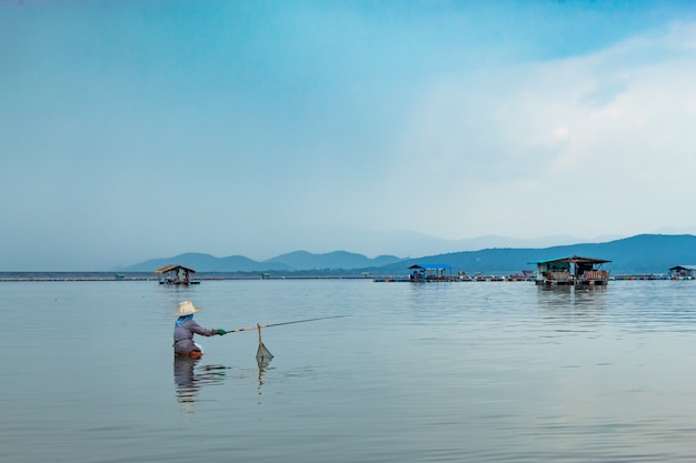 I pescatori si siedono a pescare nell&#39;acqua.