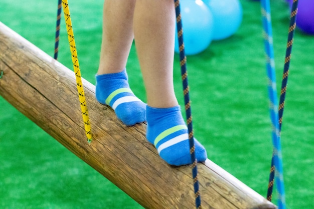 I piedi dei bambini al parco giochi con ponte oscillante.