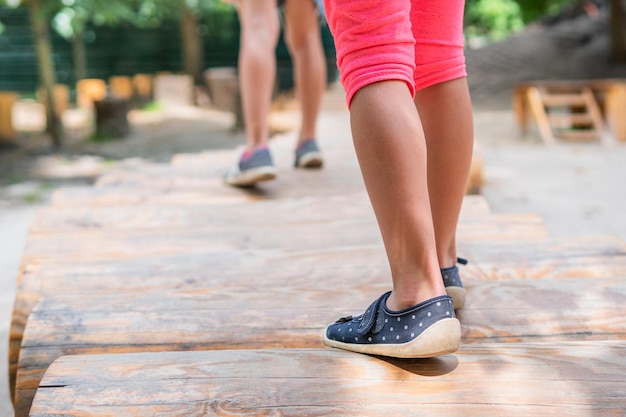 i piedi dei bambini camminano sui tronchi nel parco giochi, vista dal retro, primo piano