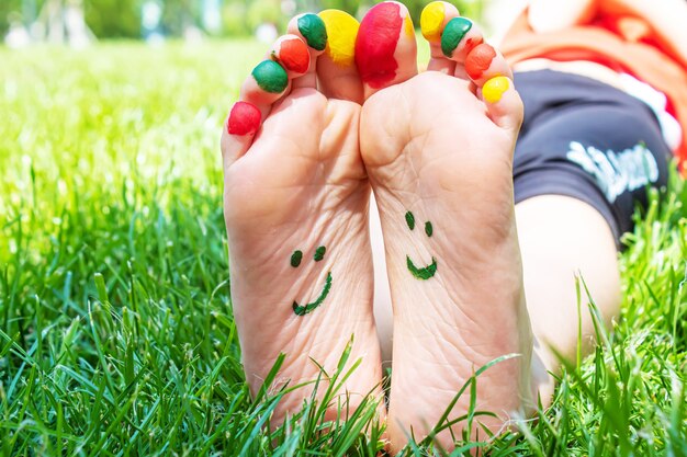 I piedi dei bambini con un motivo di vernici sorridono sull'erba verde. Messa a fuoco selettiva. natura.