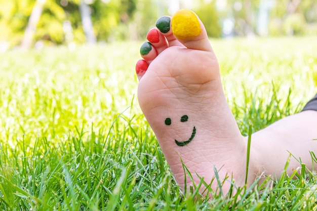 I piedi dei bambini con un motivo di vernici sorridono sull'erba verde. Messa a fuoco selettiva. natura.