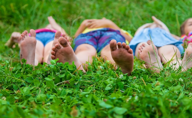 I piedi dei bambini giacciono sull'erba. Messa a fuoco selettiva. Ragazzo.