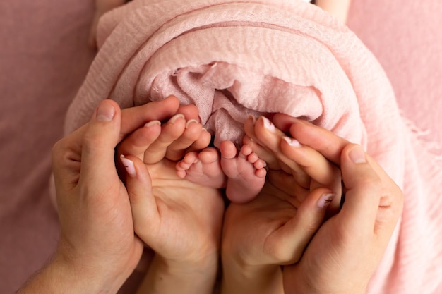 I piedi dei bambini nelle mani dei genitori. Gambe di un minuscolo neonato in primo piano sulle braccia. Famiglia e chi