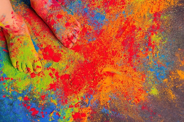 i piedi dei bambini sono tutti cosparsi di colori Holi luminosi multicolori, copia spazio.