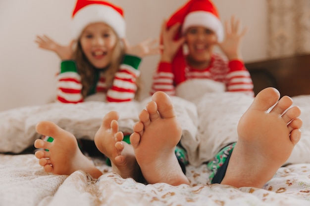 I piedi del bambino spuntano da sotto la coperta. Due bambini di età diverse. Piedi da vicino. Concetto di natale e capodanno