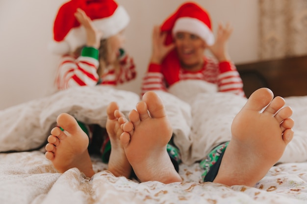 I piedi del bambino spuntano da sotto la coperta. Due bambini di età diverse. Piedi da vicino. Concetto di natale e capodanno