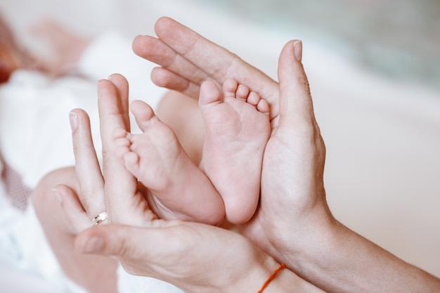 I piedi del neonato sul primo piano femminile delle mani.