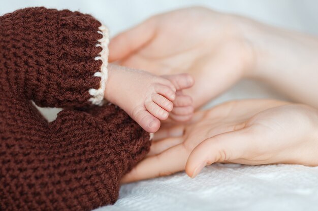 I piedi del neonato sulle mani della mamma