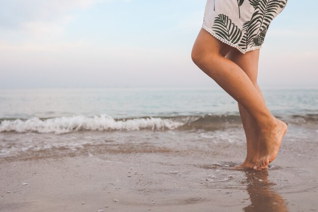 I piedi della donna camminano la vita lenta e si rilassano sulla spiaggia tropicale di sabbia con il fondo del cielo blu. Vacanza e concetto di vacanza.