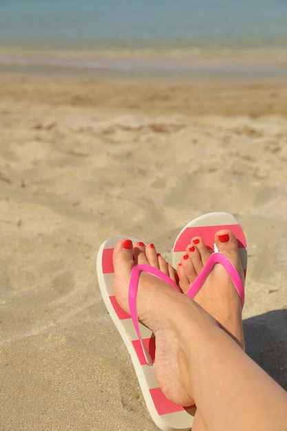 I piedi della donna con le infradito sulla sabbia