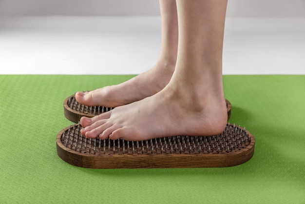 I piedi della donna stanno sul tabellone con unghie affilate Sadhu board yoga pratica prove di dolore salute