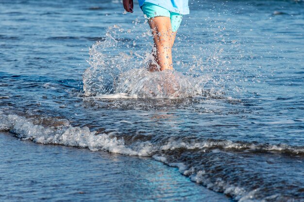 I piedi di un giovane che cammina lungo la riva del mare