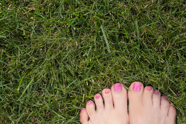 i piedi femminili a piedi nudi stanno sull'erba verde