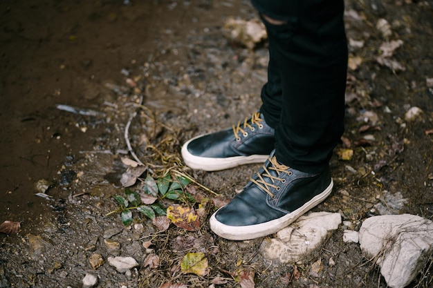 I piedi maschili in scarpe da ginnastica nere sono a terra vicino al primo piano dell'acqua