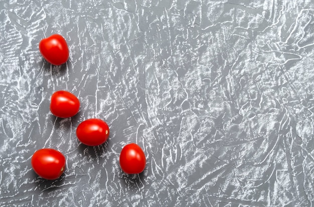 I pomodorini sono luminosi, succosi e maturi su un grigio