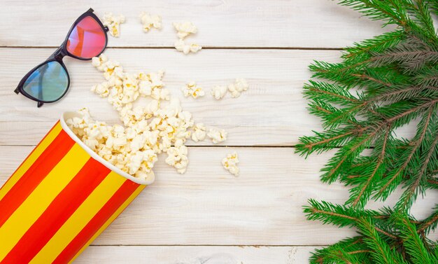 I popcorn fuoriescono dai bicchieri per il cinema e dai rami degli alberi di Natale