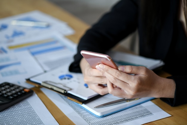 I quadri femminili stanno usando lo smartphone nell&#39;ufficio.