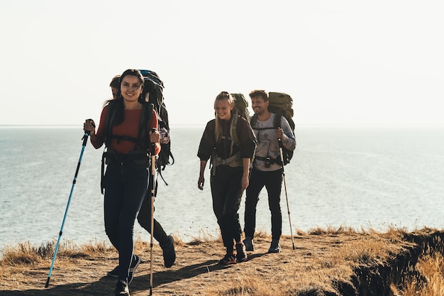 I quattro turisti con gli zaini che camminano lungo la riva del mare