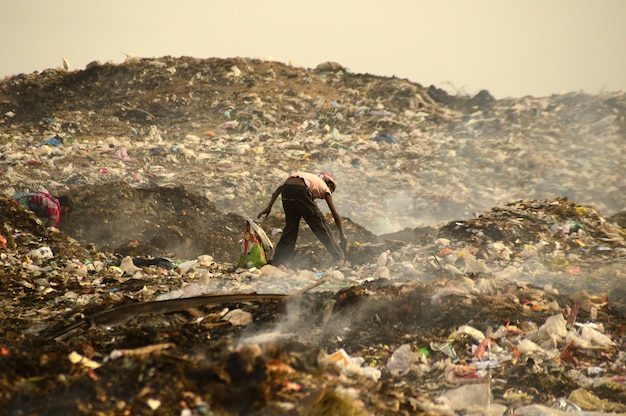 I raccoglitori di stracci cercano materiale riciclabile nella spazzatura Terra e inquinamento atmosferico in India