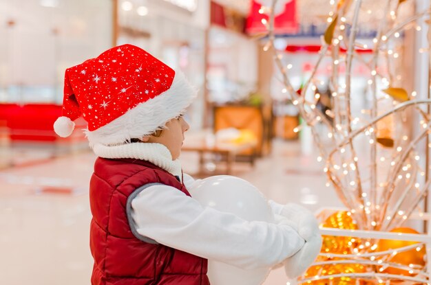 I ragazzi con il cappello di Babbo Natale sorridono e tengono in mano un palloncino bianco nella vendita dello shopping natalizio del mercato