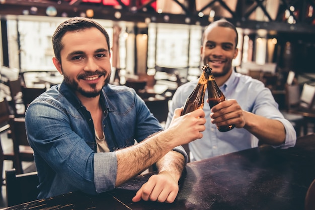 I ragazzi tintinnano bottiglie di birra mentre riposano nel pub.