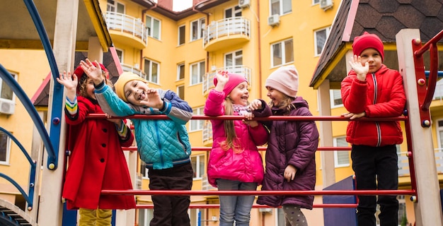 I ragazzini e le ragazze al parco giochi in autunno I bambini felici sono in piedi insieme e posano per la telecamera