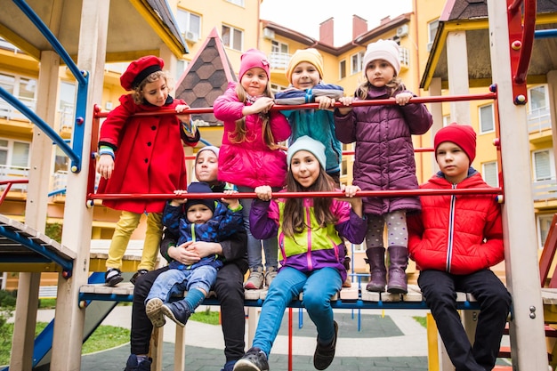 I ragazzini e le ragazze al parco giochi in autunno I bambini felici sono in piedi insieme e posano per la telecamera