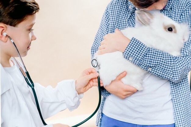 I ragazzini stanno giocando veterinario con un coniglio. concetto veterinario di amore animale